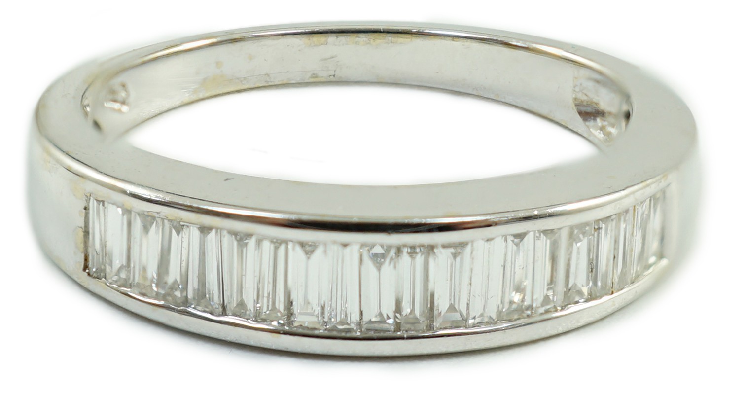 A modern white metal and graduated baguette cut channel set diamond half hoop ring, size M/N gross weight 3.7 grams.